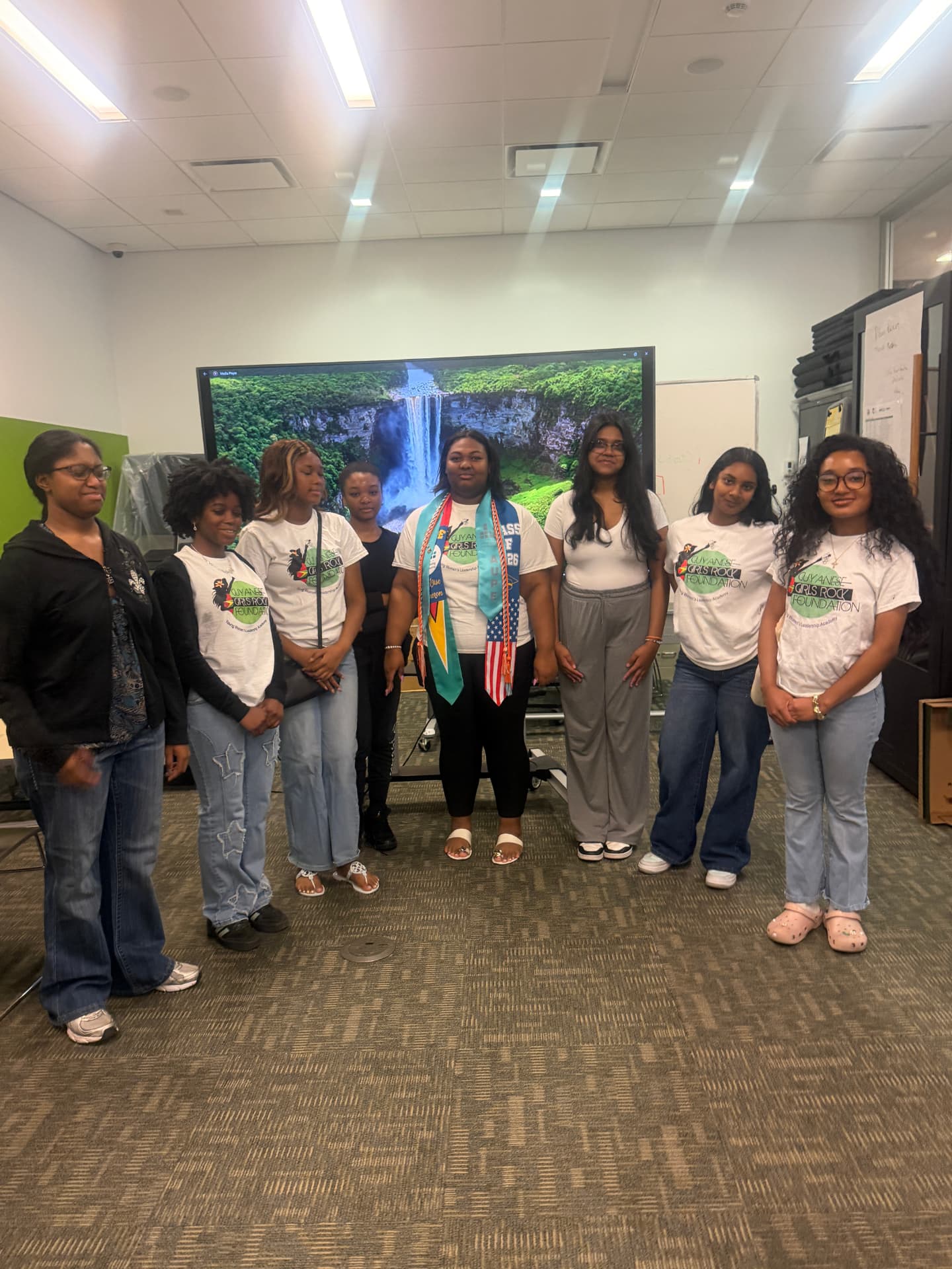 Mentors and scholars beside a waterfall display