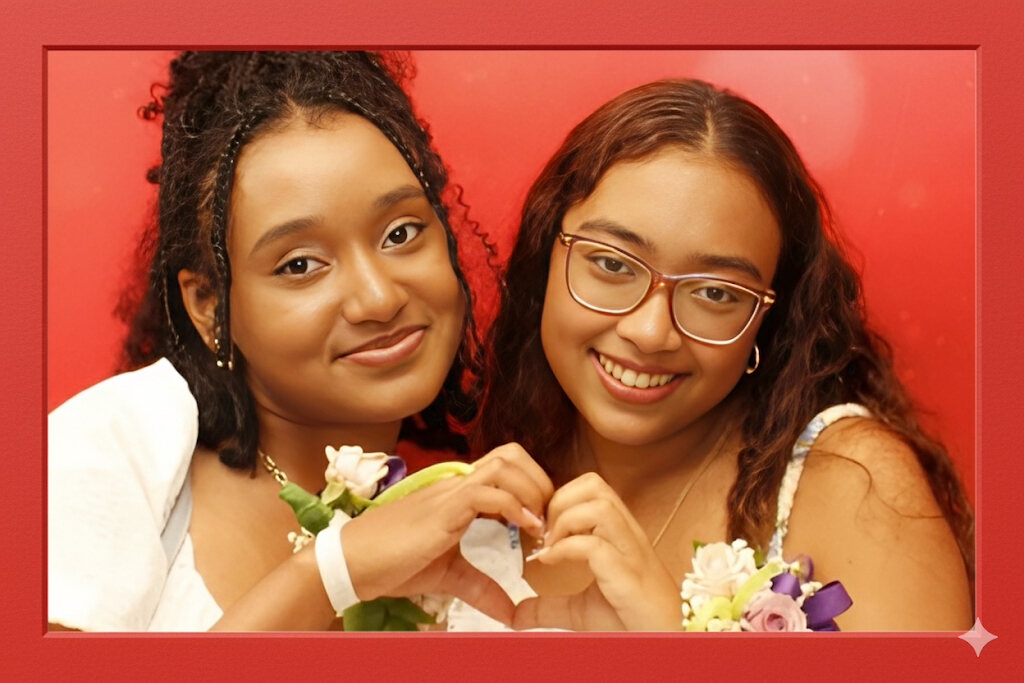 Two young women in corsages making a heart shape with their hands