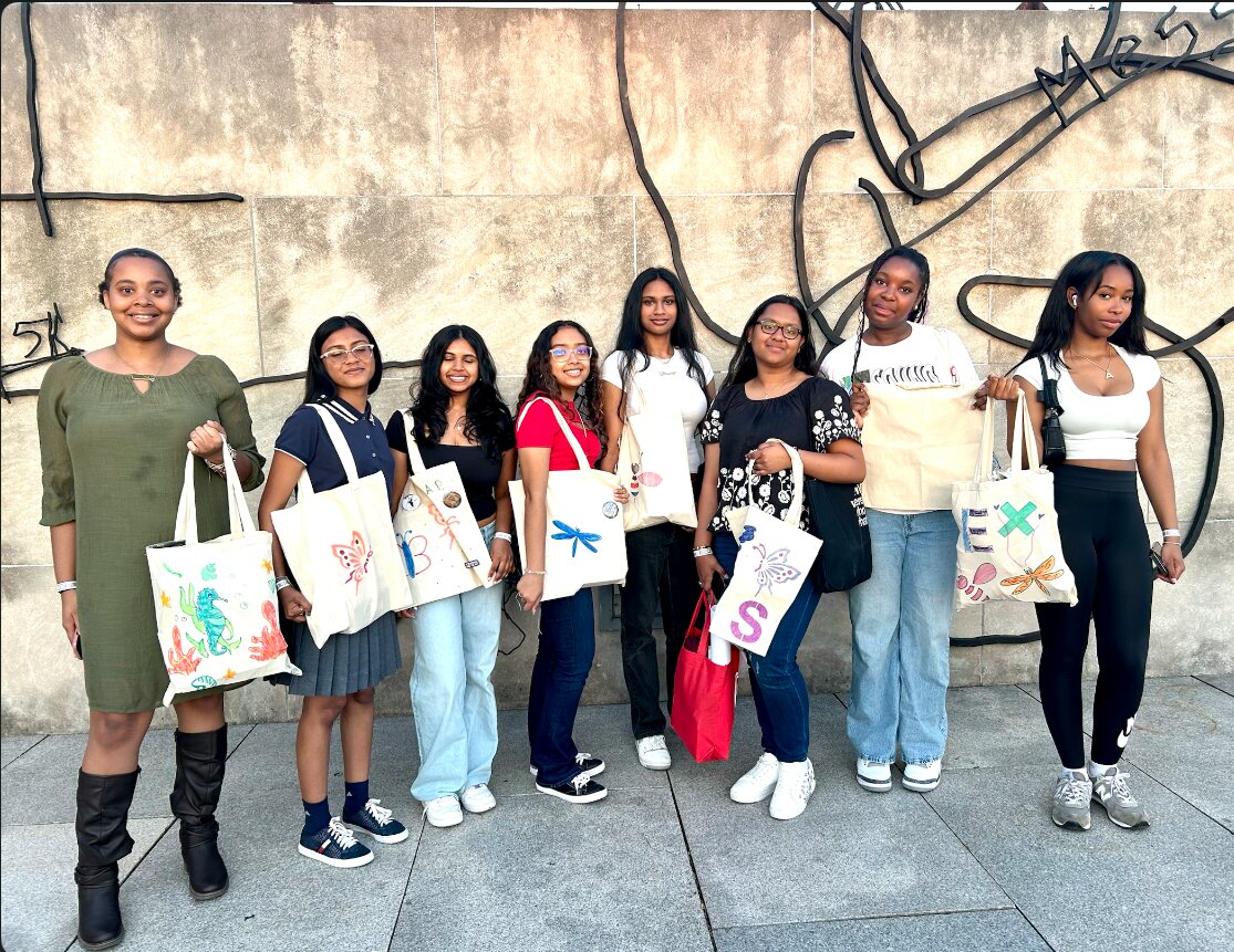 Eight scholars holding their painted tote bags